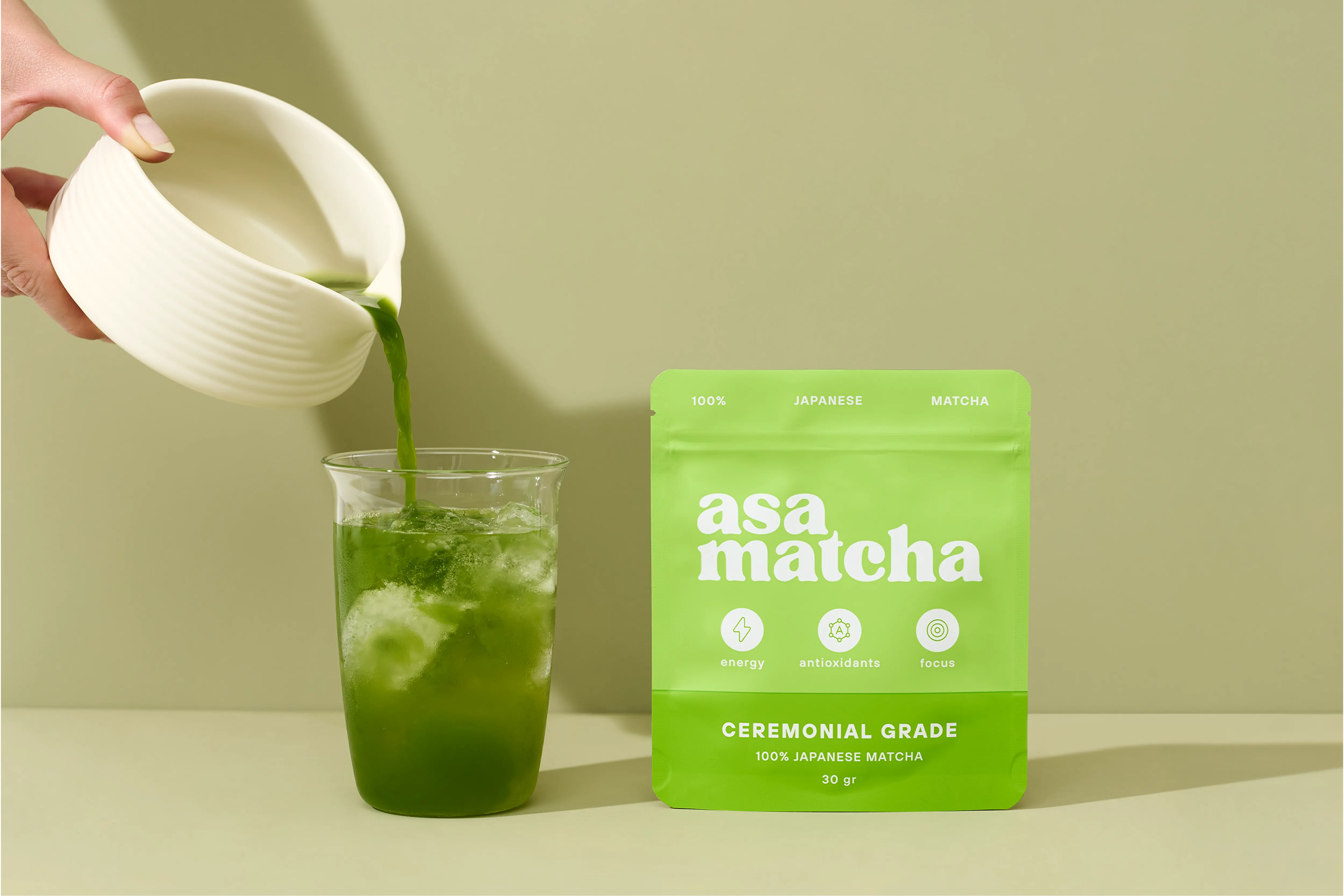 Iced matcha poured from a ceramic jug beside an Asa Matcha ceremonial grade pouch