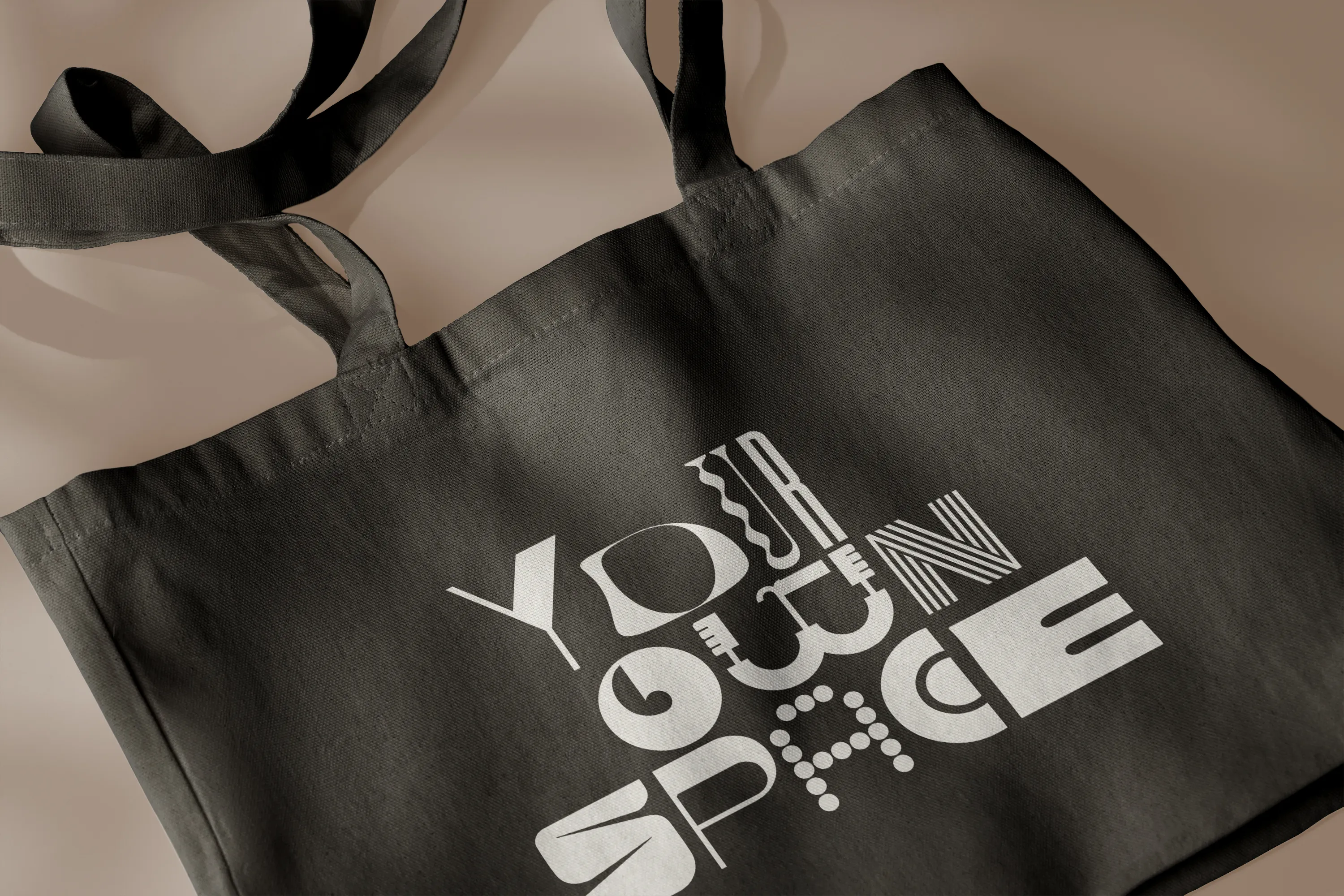 Dark canvas tote bag printed with “Your own space” in custom display lettering
