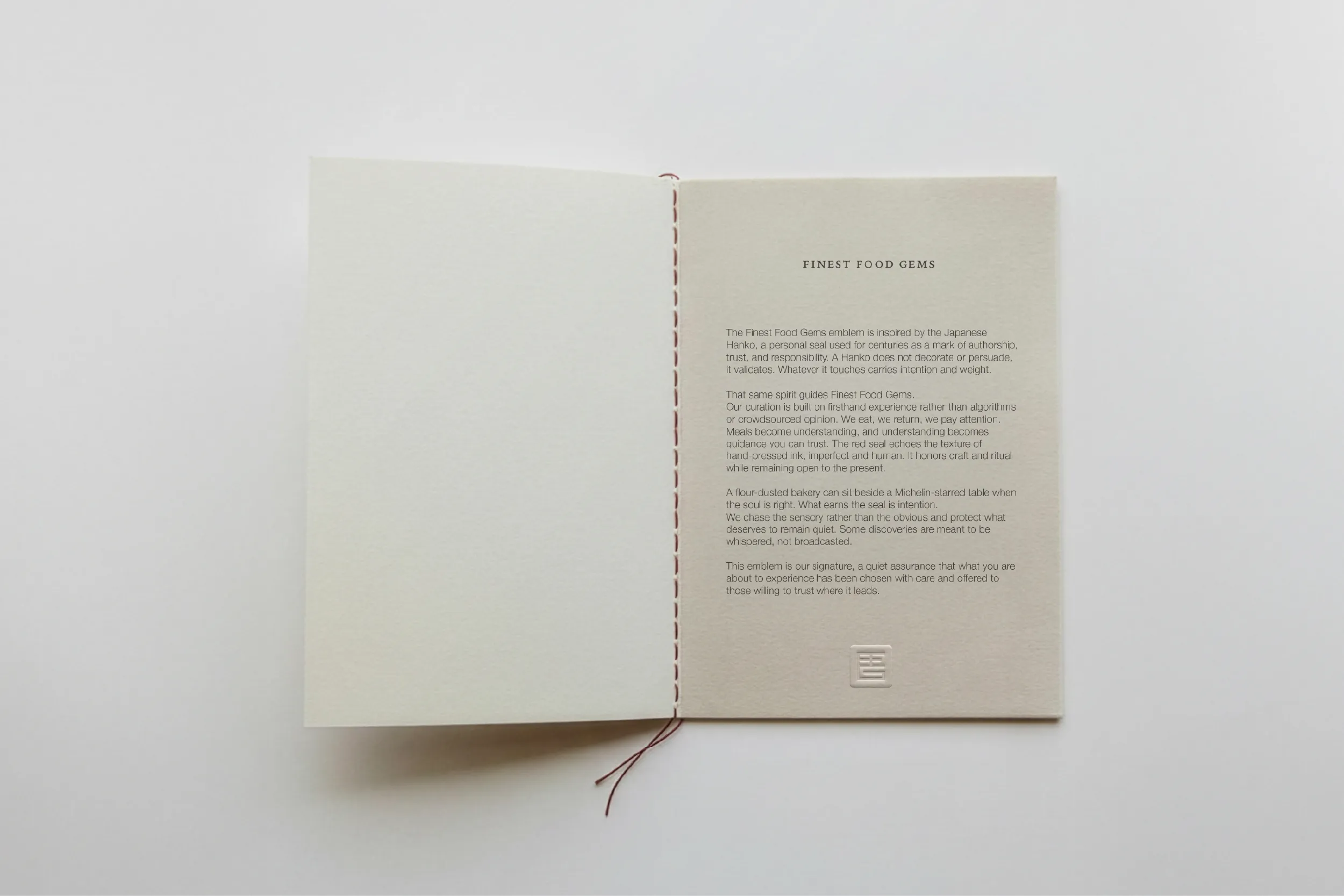 Open booklet stitched with red thread, with an embossed seal under the text