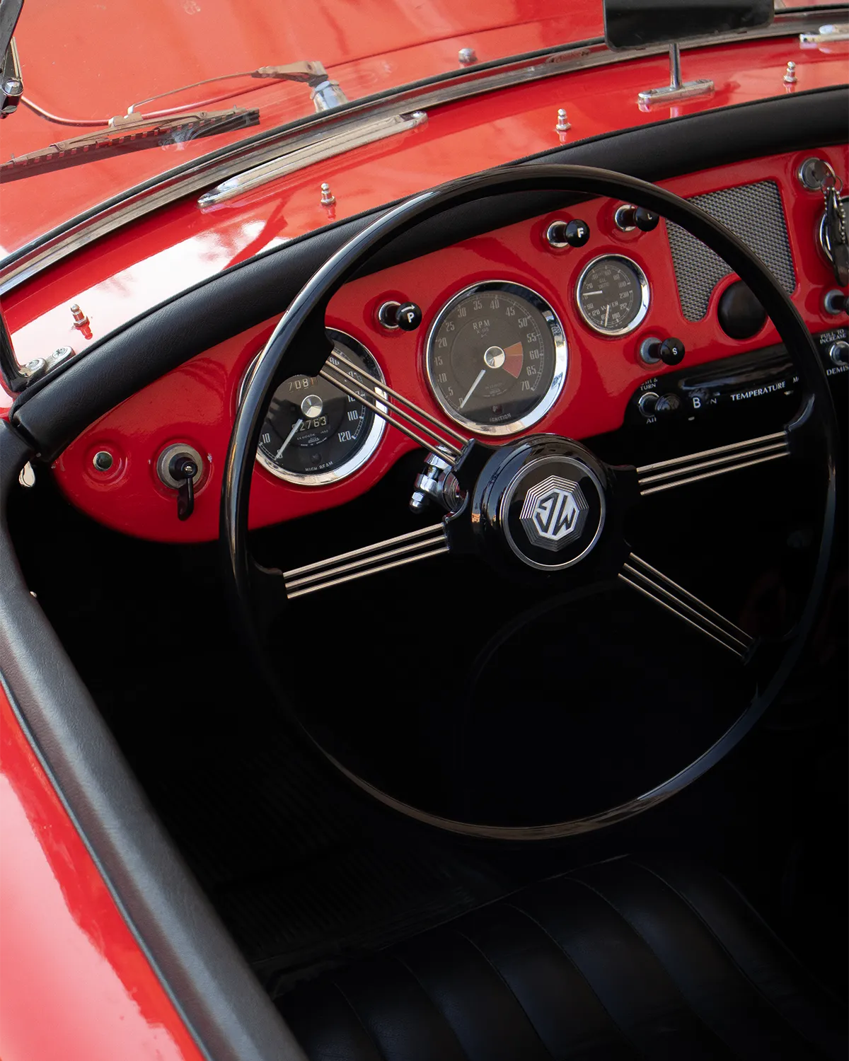 Dashboard and black steering wheel of a red vintage MGA roadster