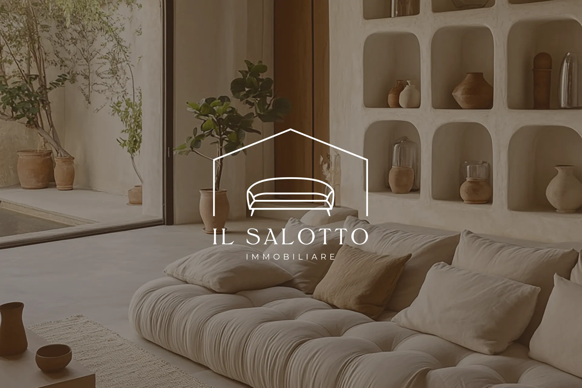 Il Salotto Immobiliare logo, a sofa inside a house outline, over a neutral living room