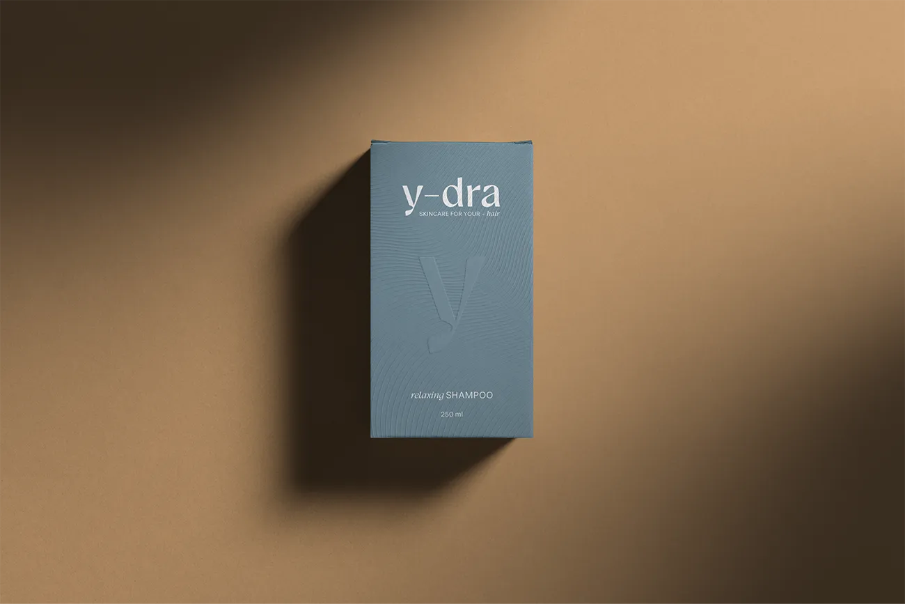 Slate blue Y-dra relaxing shampoo box with an embossed y on a tan background